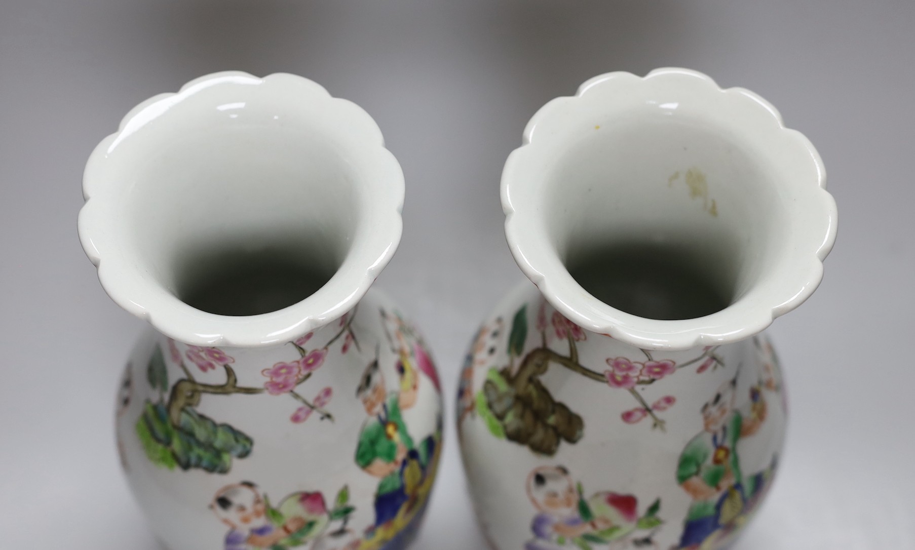 A pair of Chinese Famille Rose ‘boys’ vases, 25cms high